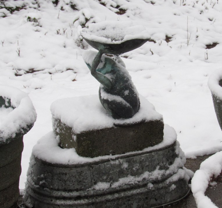 Photo of frog statue in snowy garden